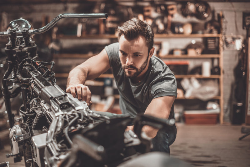 年轻的男人修理摩托车