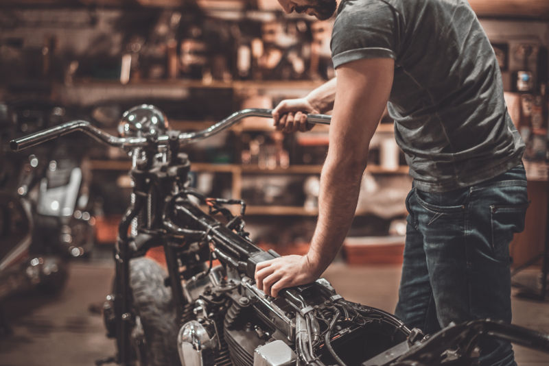 年轻的男人正在修理摩托车