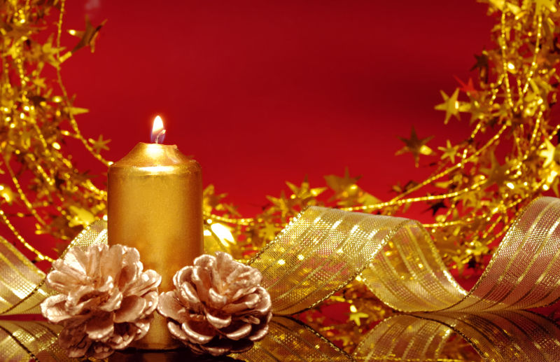 红色背景前的的金色圣诞装饰品和蜡烛