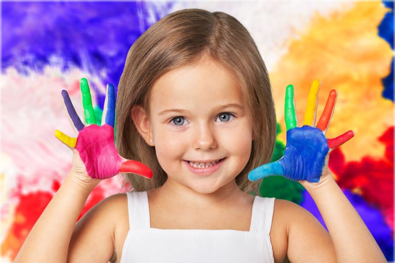 彩色背景下开心快乐的玩颜料小女孩