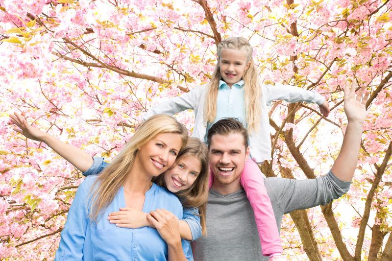在开花的春季树林中的开心的一家人