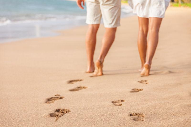沙滩情侣在夕阳赤脚行走时放松