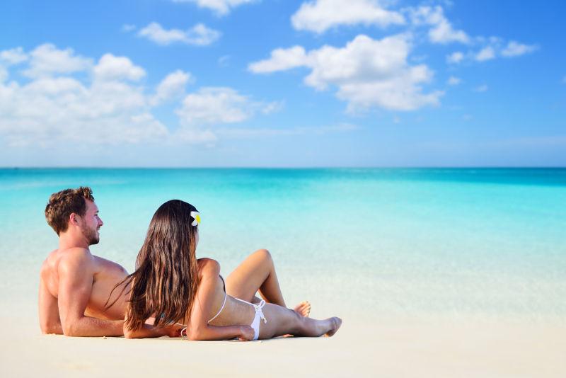 快乐的情侣在阳光海滩上晒日光浴