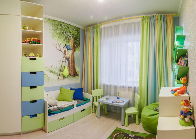 放着儿童床和小桌子小椅子的以绿色为主色调的房间