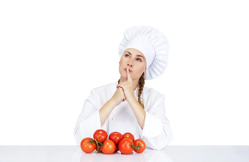 年轻的女厨师为意大利菜展示西红柿