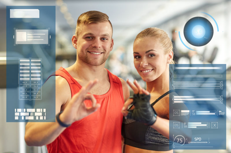 微笑的男人和女人在虚拟图表上显示健身房的手势