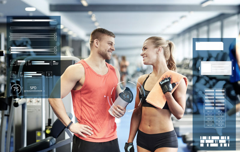 微笑的男人和女人用蛋白质摇晃瓶和毛巾在健身房谈论虚拟图表