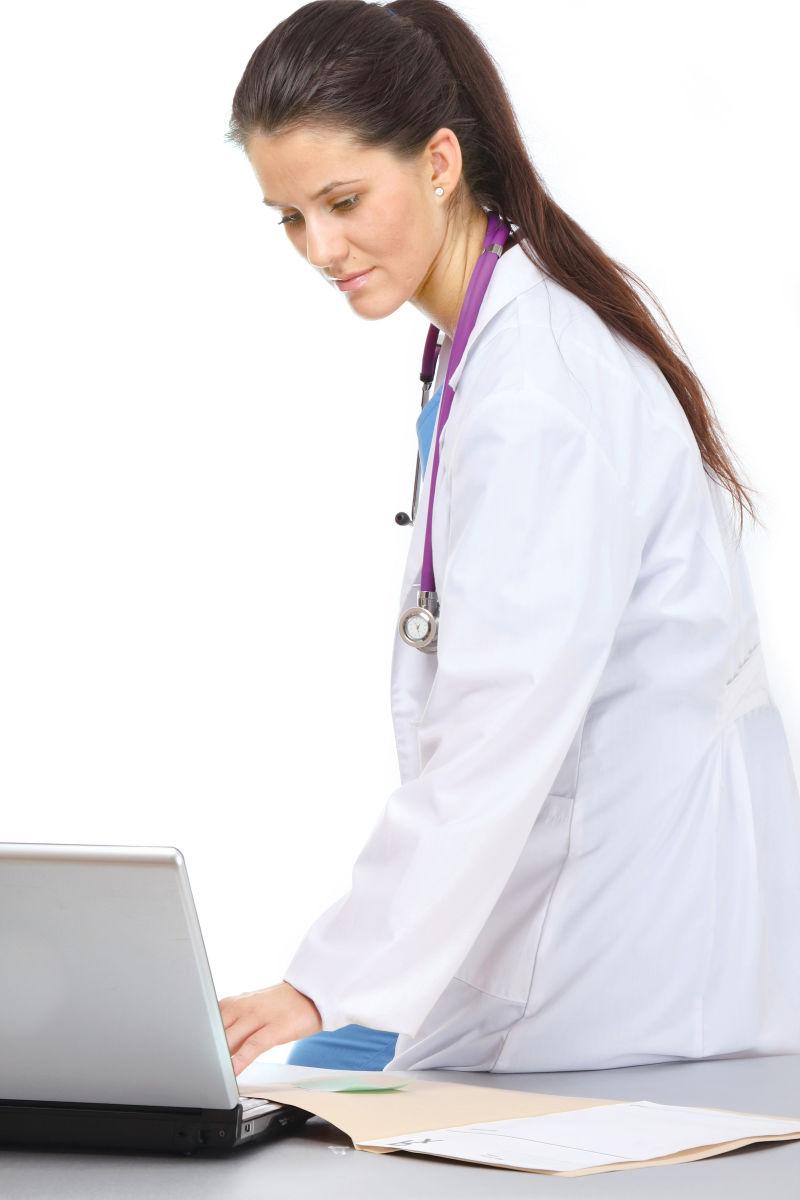 一位身着白色大衣的女医生在笔记本电脑前