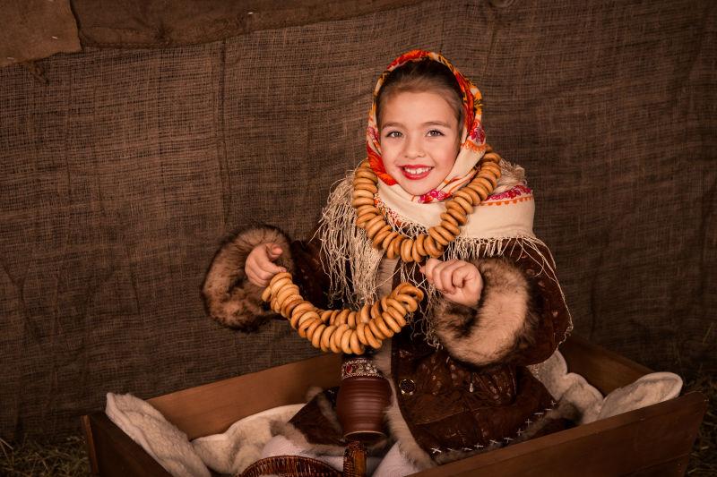 美丽的俄罗斯女孩披肩坐在一辆带百吉饼的手推车里