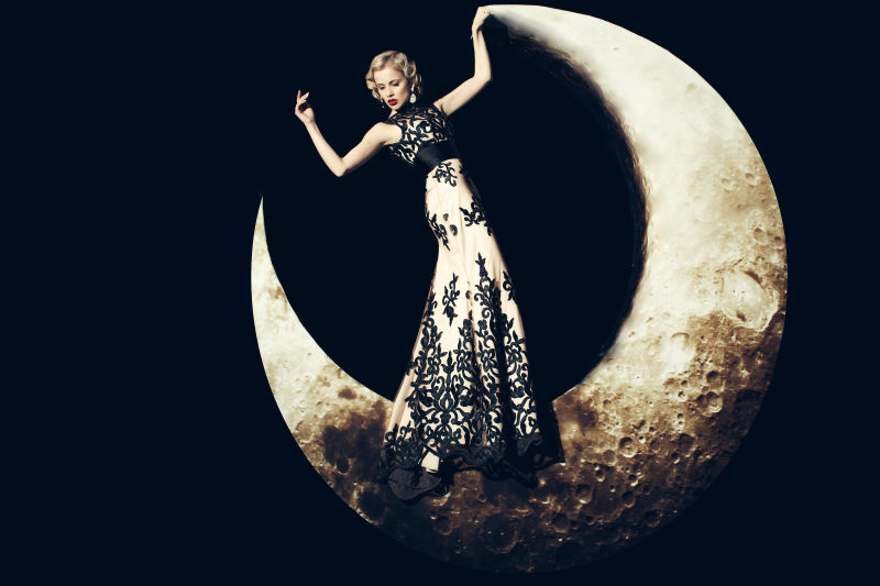 黑色背景上站在月亮上的复古美女