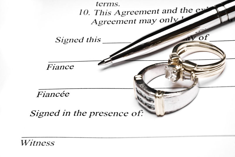 婚前协议上的钢笔和结婚戒指