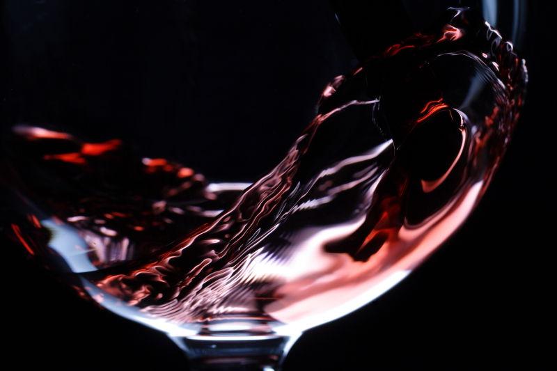 黑色背景下的酒杯倒入红葡萄酒