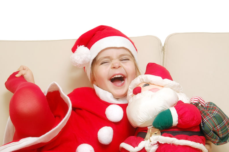 沙发上抱着圣诞老人玩具大笑的小孩