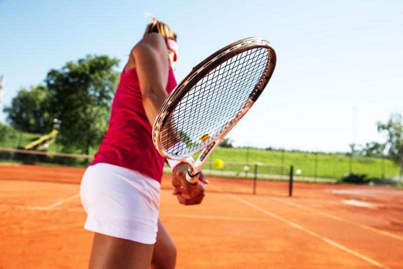 网球场上年轻女子打网球