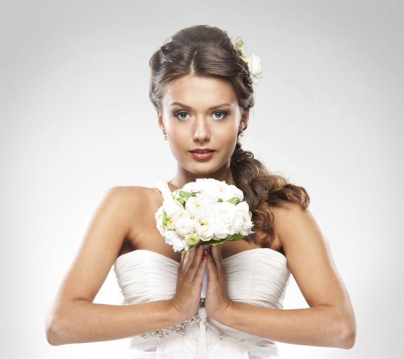 双手夹着白色花束的新娘
