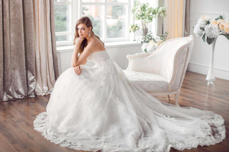美丽的新娘穿着漂亮的婚纱坐在沙发上