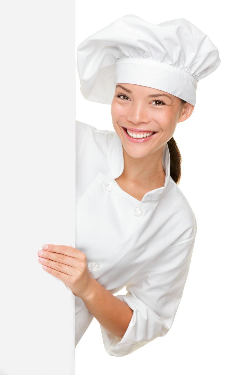 微笑着快乐地拿着空白的白纸符号的女厨师在白色背景上孤立