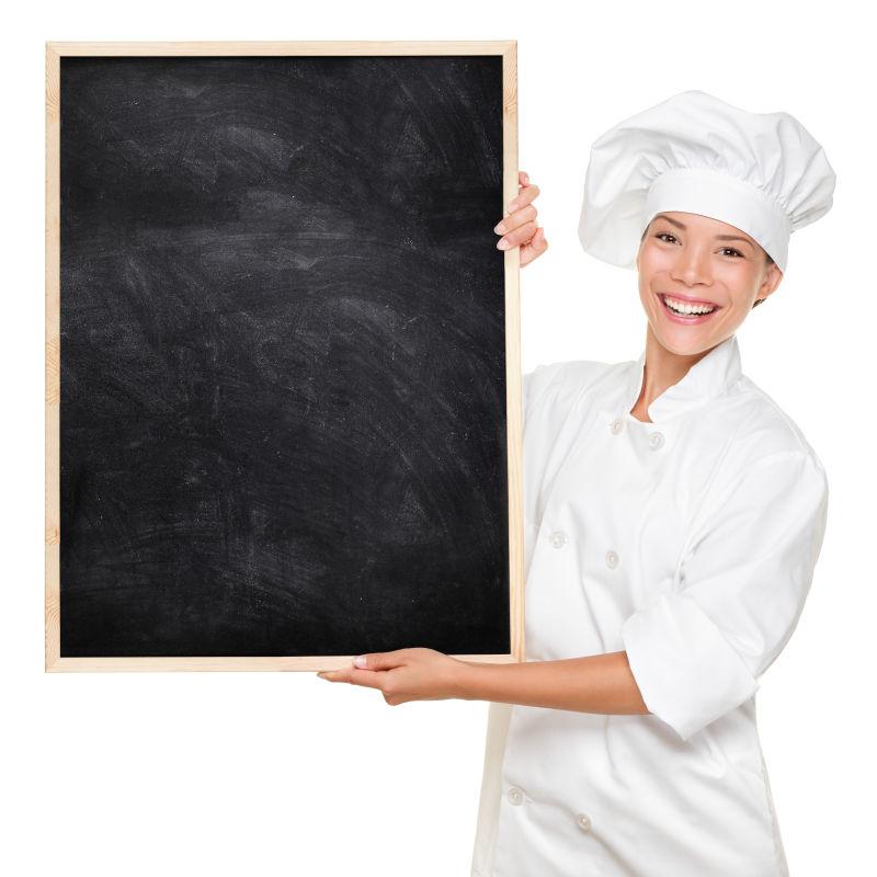 快乐的亚洲白种女厨师在白色背景下用漂亮的纹理黑板做广告