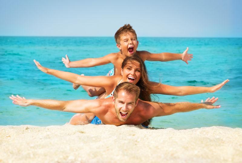 沙滩上趴在男人背上的妻子和儿子