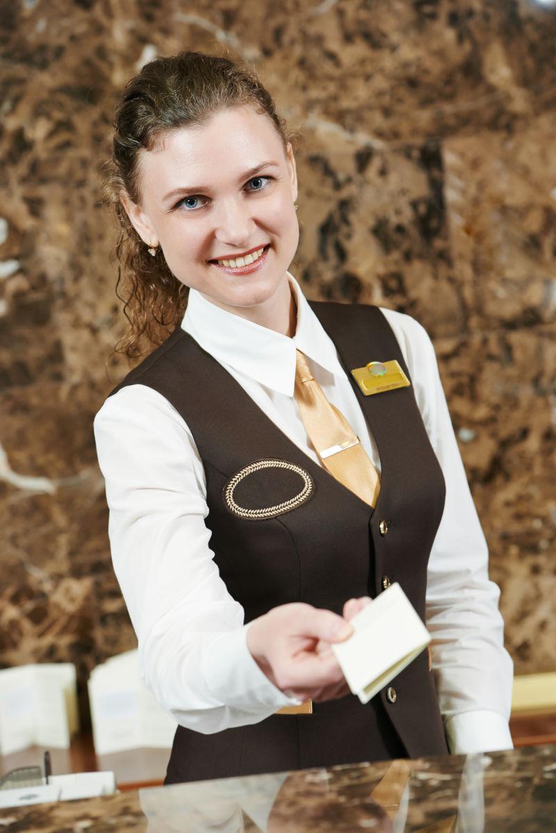 微笑女接待员向客人传递钥匙卡