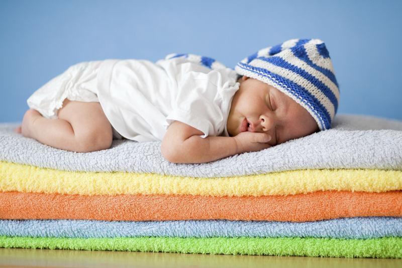 在彩色毛巾堆上睡新生婴儿