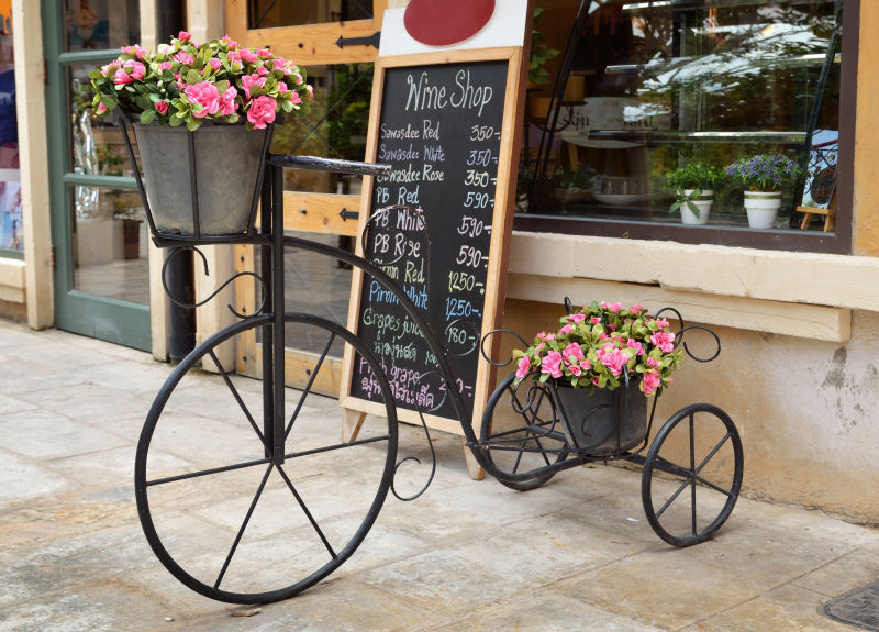 店铺门口装饰着花卉的古董三轮车