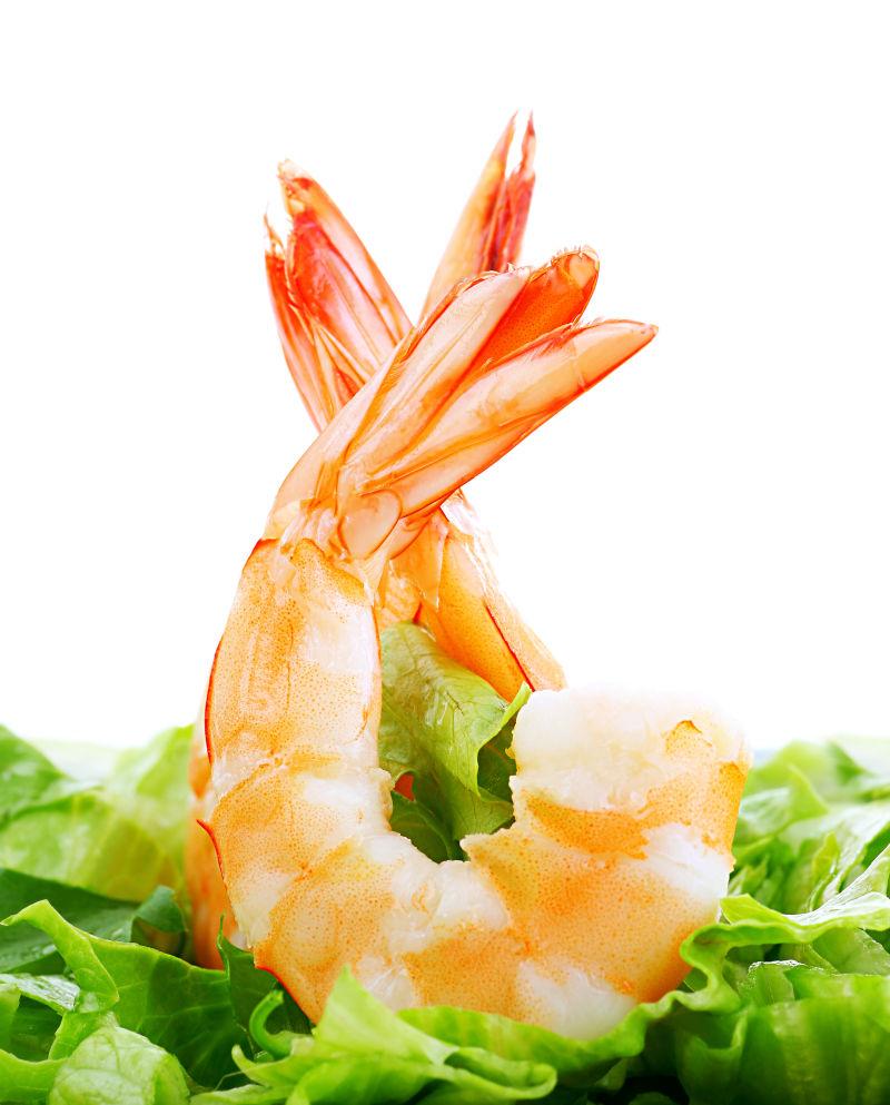白色背景下新鲜的虾与绿色蔬菜沙拉