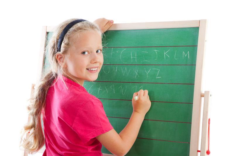 一个小女孩在黑板上写英文字母