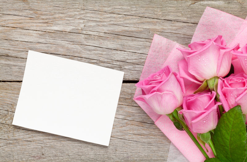 粉红玫瑰花和空白贺卡在木桌上