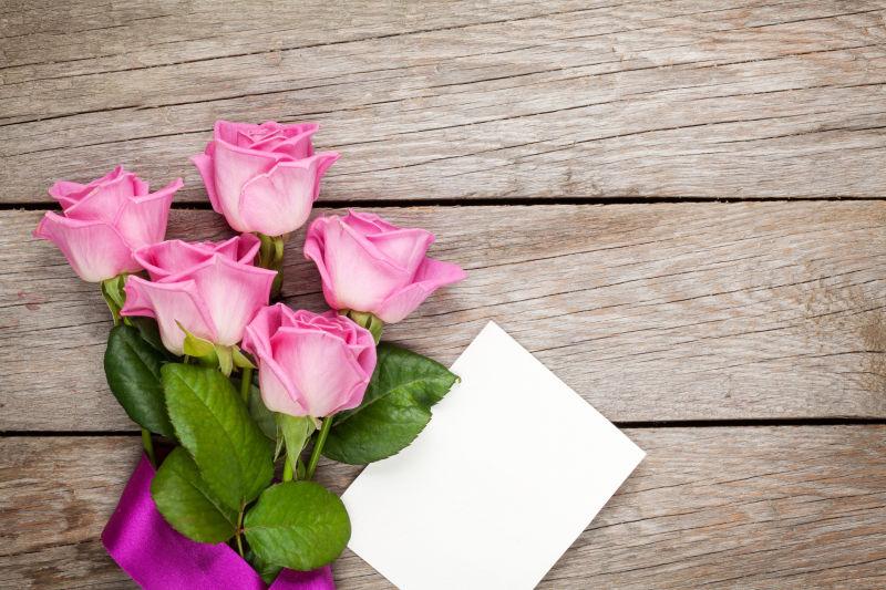 在木桌上粉红玫瑰和情人节空白贺卡