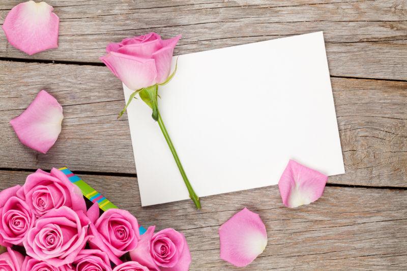 情人节贺卡和粉红色玫瑰在木桌上