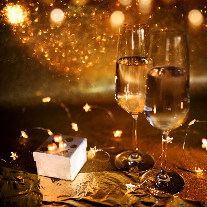 喜庆的圣诞静物伴着香槟和礼物在金色闪闪发光的背景下