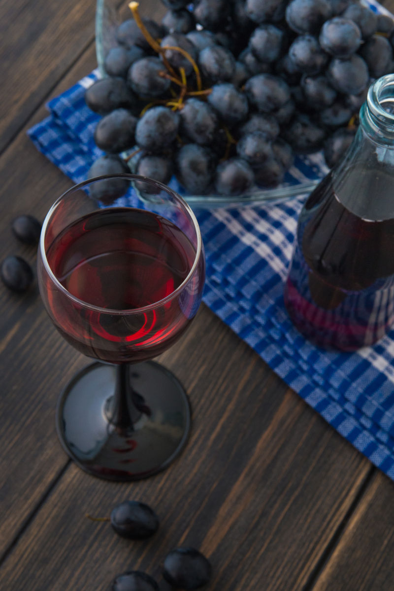 木桌上的葡萄酒与一堆葡萄