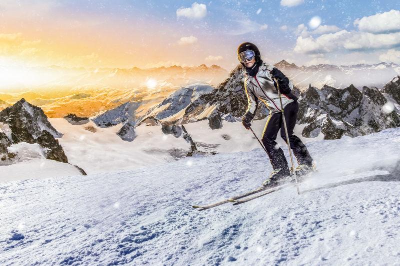 夕阳下的群山背景下在山上滑雪的人