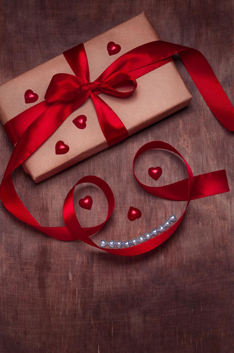 木制背景上红色丝带装饰的情人节礼物