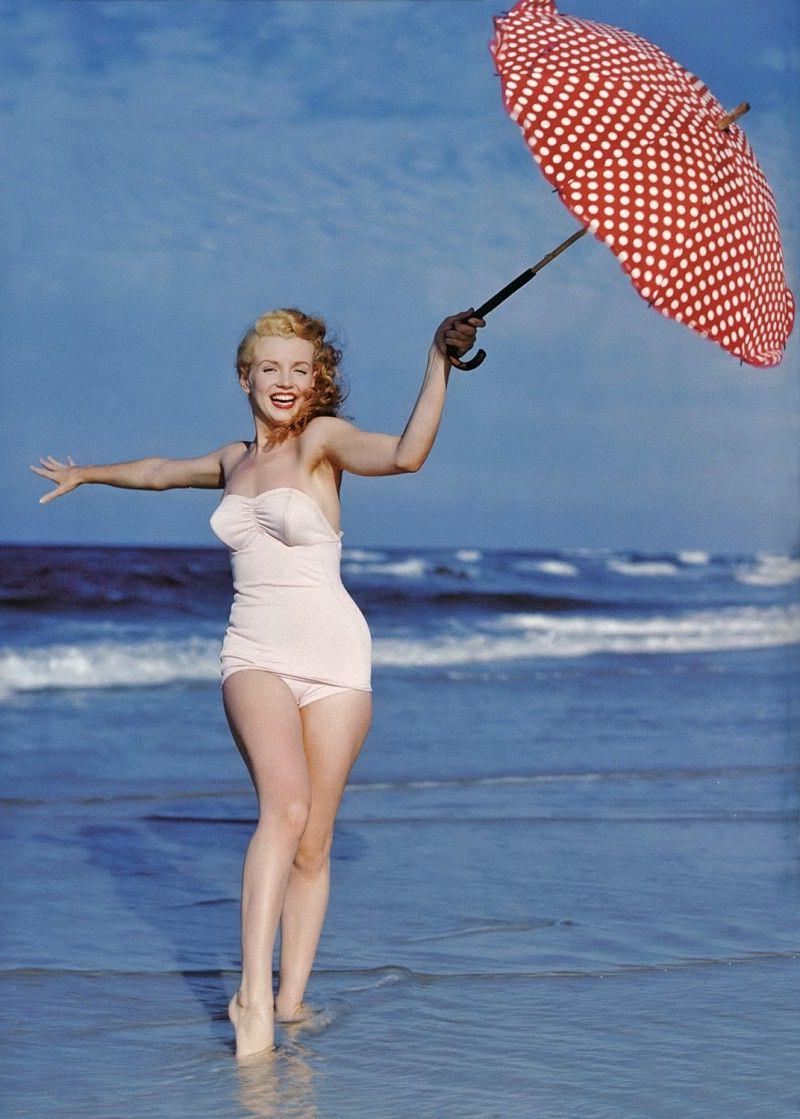 拿着雨伞在海滩上奔跑的美女