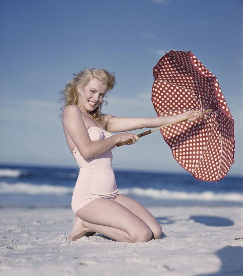 海滩上的年轻拿着伞的时尚女人