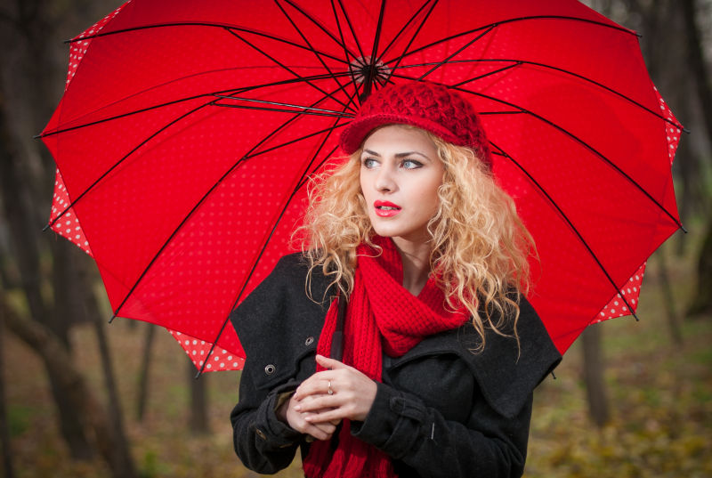 手拿红色雨伞戴着红色帽子的漂亮女子