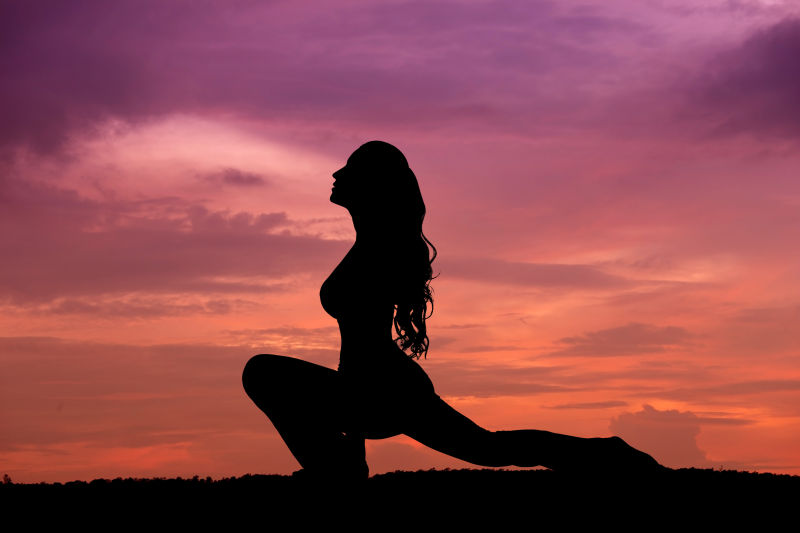 日落时分压腿做瑜伽女人的剪影