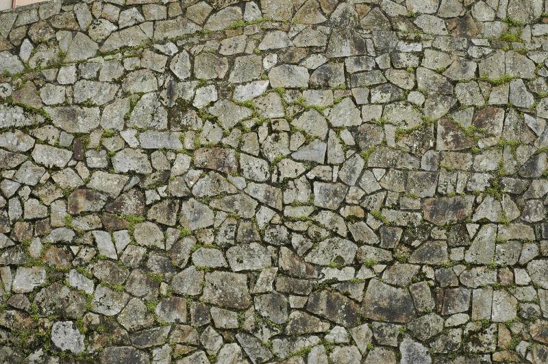 石头缝长了绿草的石头墙背景