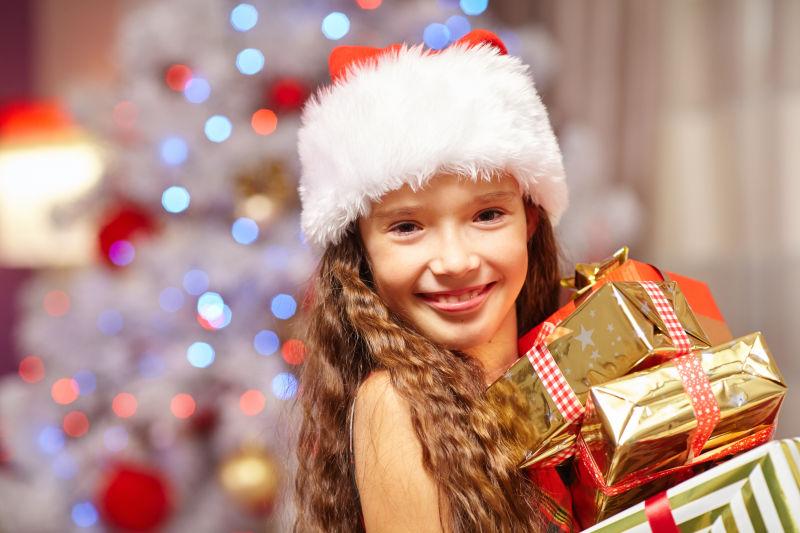 圣诞树前拿礼物的微笑女孩