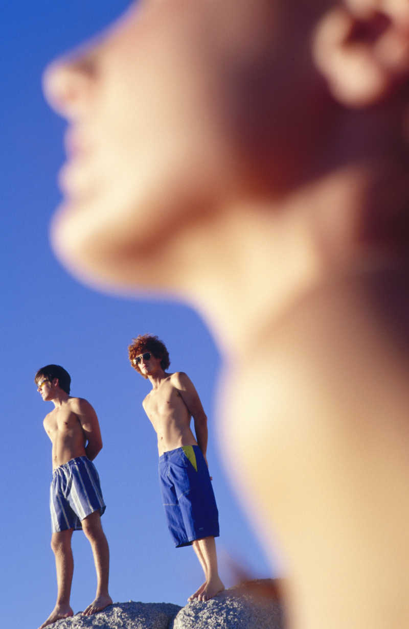 站在海滩岩石上抬头眺望远方的年轻男子