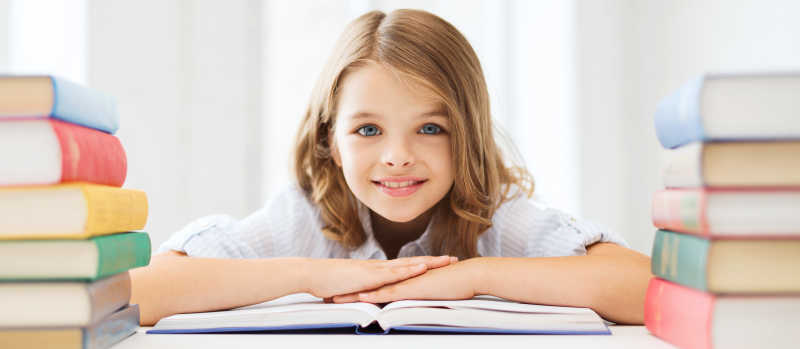 微笑的小学生面对一堆书籍很感兴趣