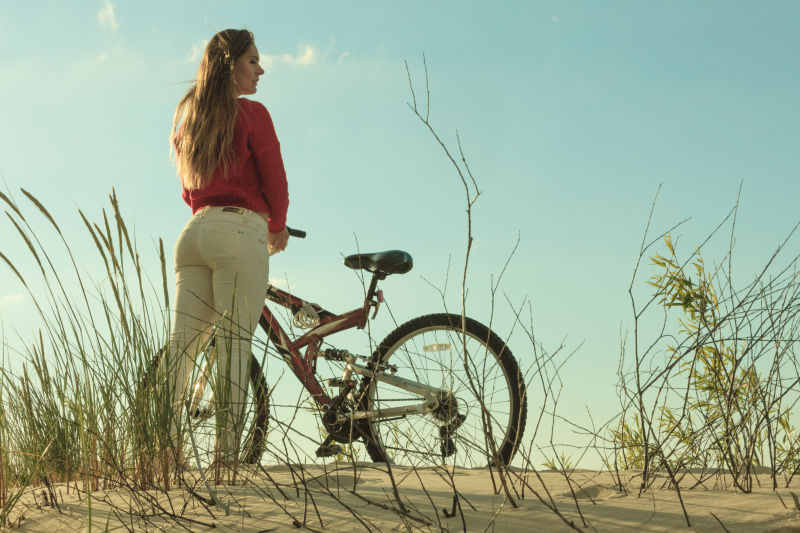 无法辨认的女子自行车在沙滩上骑行