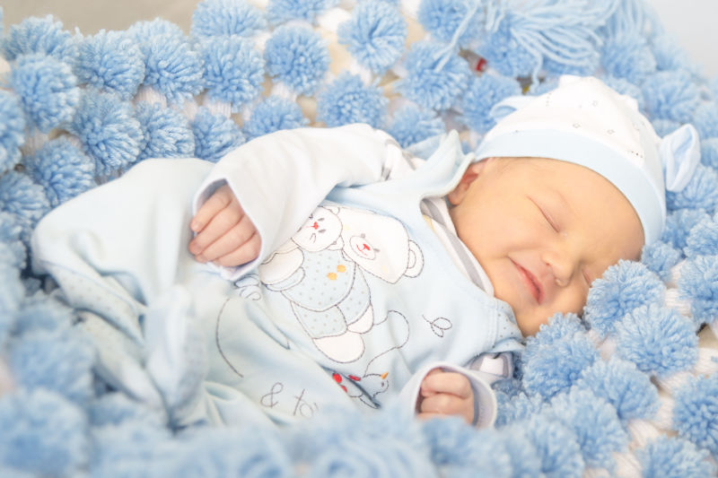 甜蜜的梦中的宝贝-新生儿两周穿着白衣服-浅蓝色睡觉-童年的概念