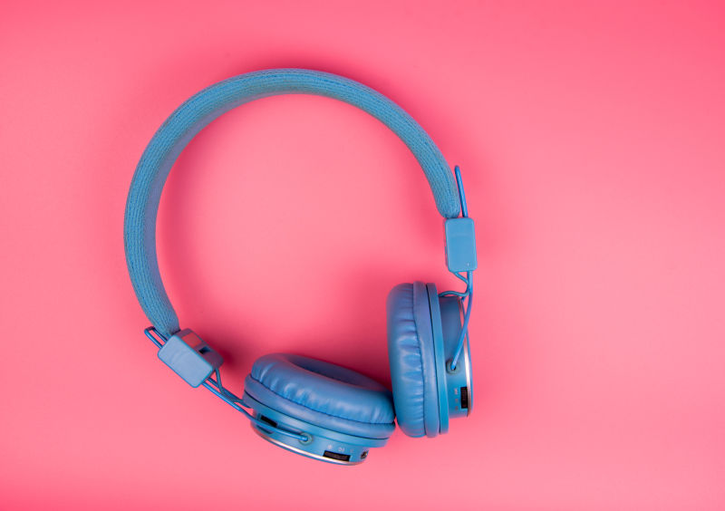 浅粉红背景的蓝色耳机复古或粉彩概念