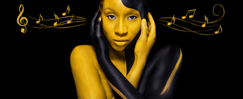 带着艺术时尚妆的快乐的非洲年轻女子迷人的女人黑黄相间的妆和音符车身上有彩色油漆