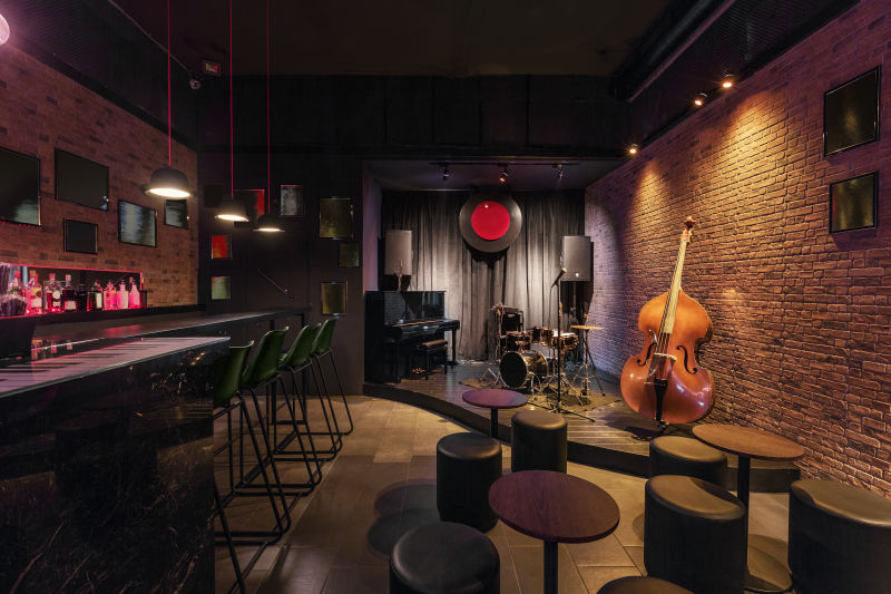 现代爵士乐酒吧室内设计舞台上有黑色钢琴和大提琴吧台上有台灯