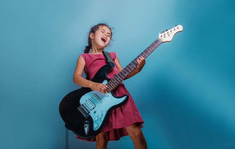 欧洲女孩十年在蓝色背景下弹吉他