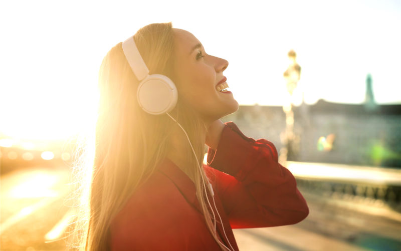 在街上散步时戴着耳机听音乐的漂亮女孩